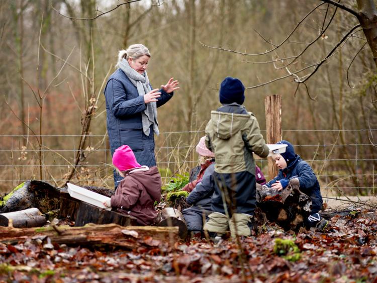 Pædagog og børn leger i naturen