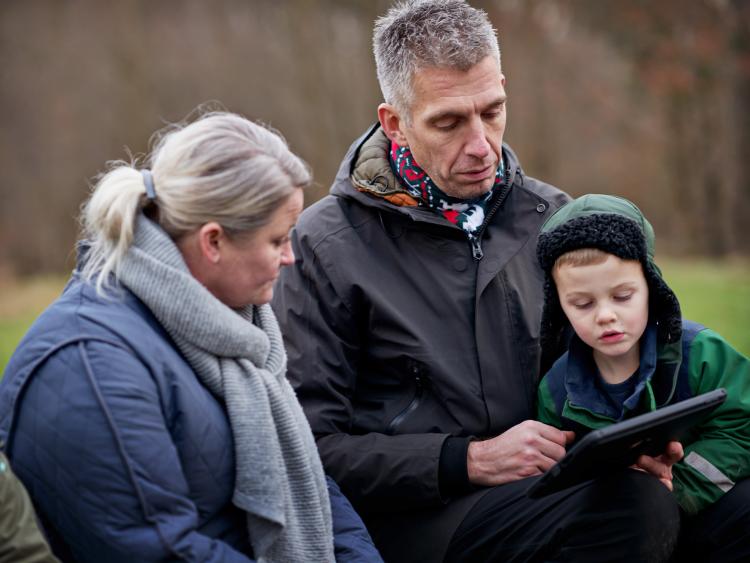 Pædagog og barn kigger på ipad i naturen